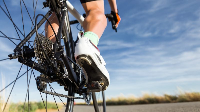 Close-up of the foot of a young man cycling on the road.